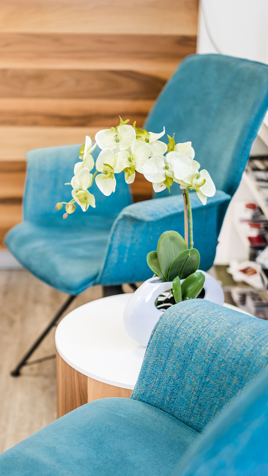 Wartebereich mit blauen Sesseln, weißem Beistelltisch und einer Orchidee im Männing Fachgeschäft Wülfrath.